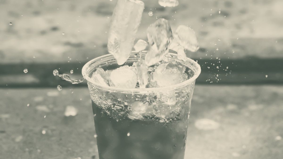 Eiswürfel fallen in einen Becher mit kaltem Kaffee und lassen ihn aufspritzen